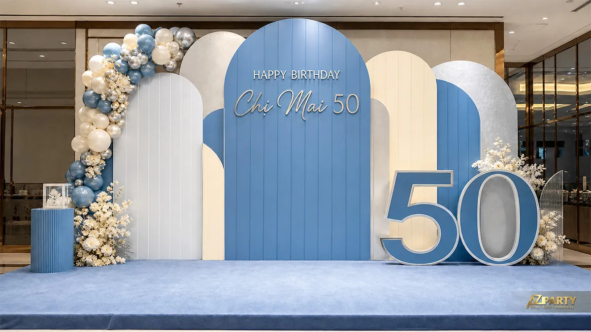 Backdrop sinh nhật chị Mai 50 tuổi tông xanh baby trắng bạc, phối số 50, bóng và hoa trắng.
