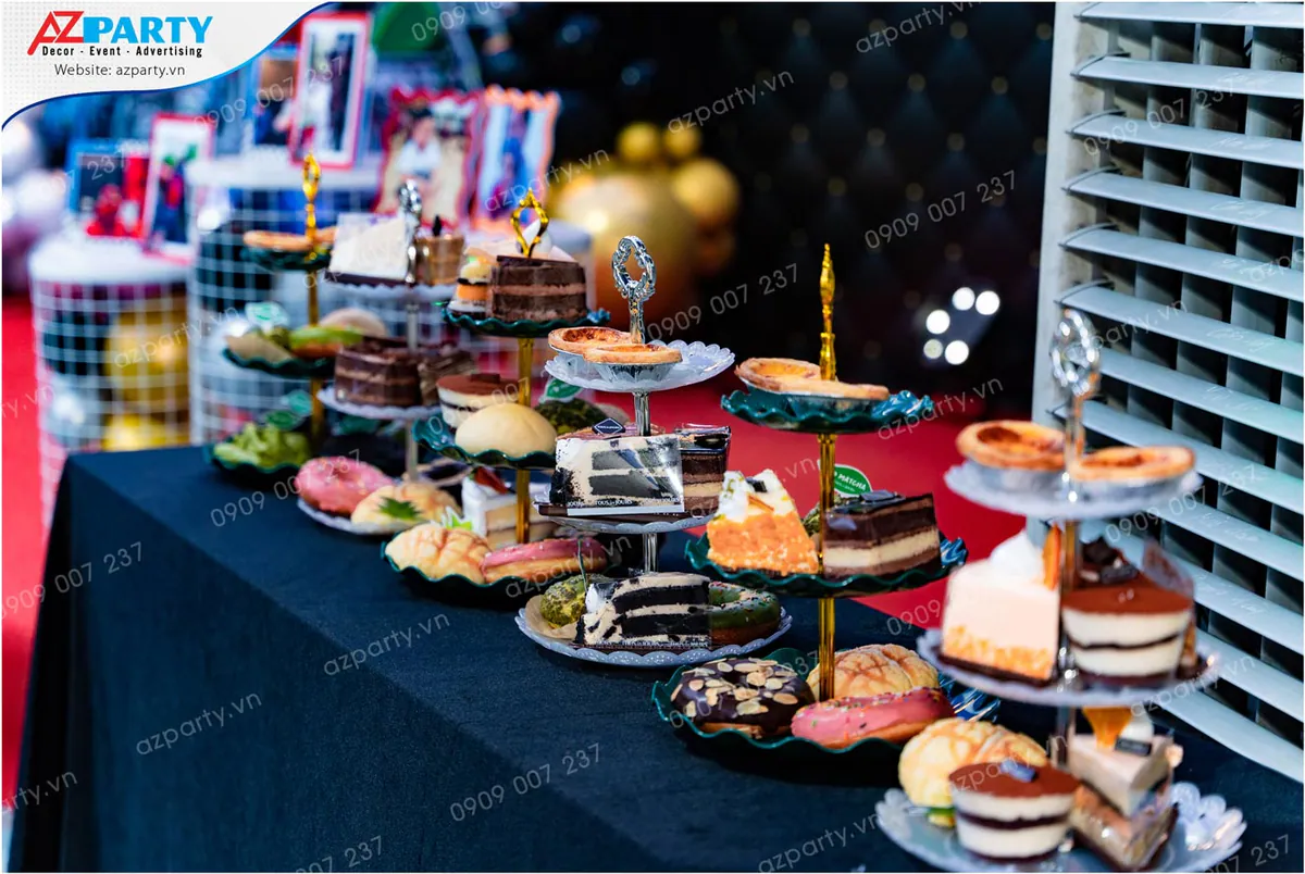 Bàn tiệc teabreak sinh nhật với đa dạng các loại bánh ngọt như tiramisu, mousse, bánh trứng tart, bánh donut được bày biện đẹp mắt trên các khay nhiều tầng.