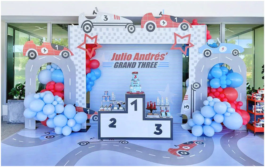 Trang trí sân khấu sinh nhật 3 tuổi cho bé Julio Andrés với chủ đề đường đua xe công thức 1, bục nhận giải số 1-2-3 làm bàn gallery đặt bánh kem và bóng bay màu đỏ, xanh dương rực rỡ.