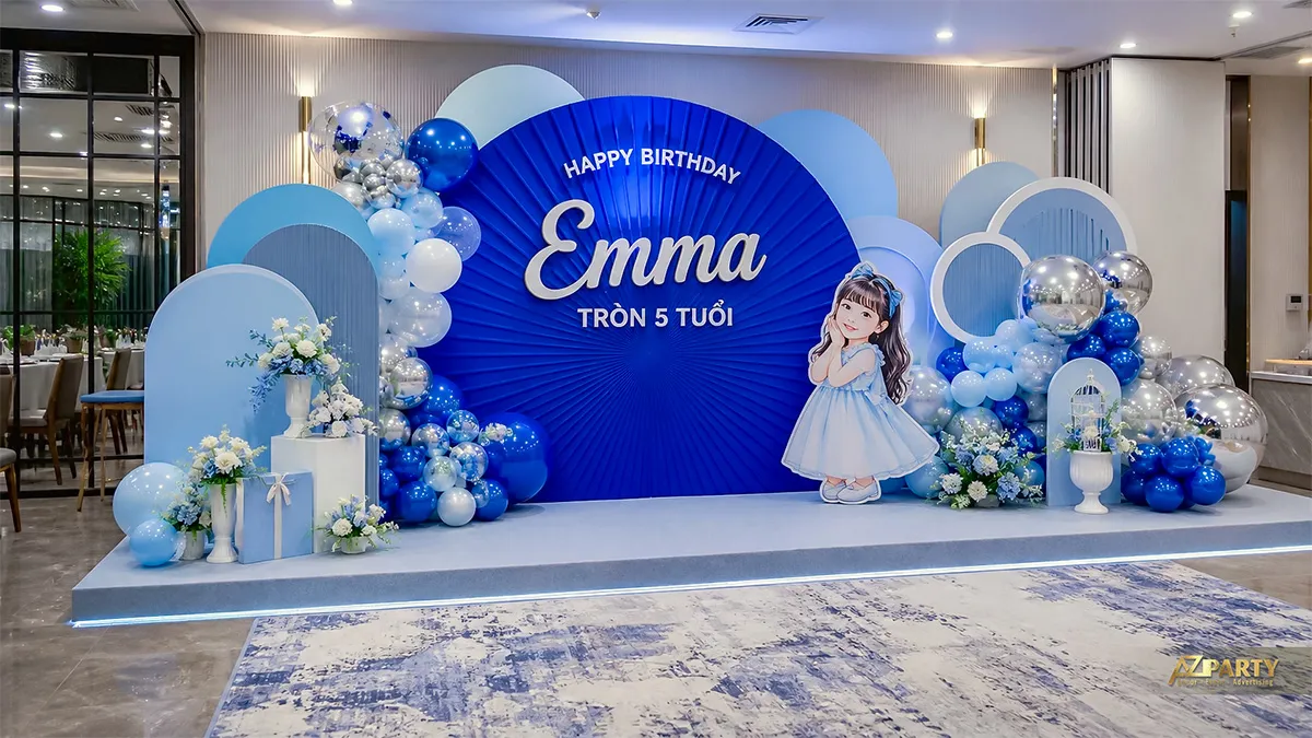 Backdrop xanh hoàng gia mừng sinh nhật Emma tròn 5 tuổi, phối bóng bạc, hoa và hình bé gái.