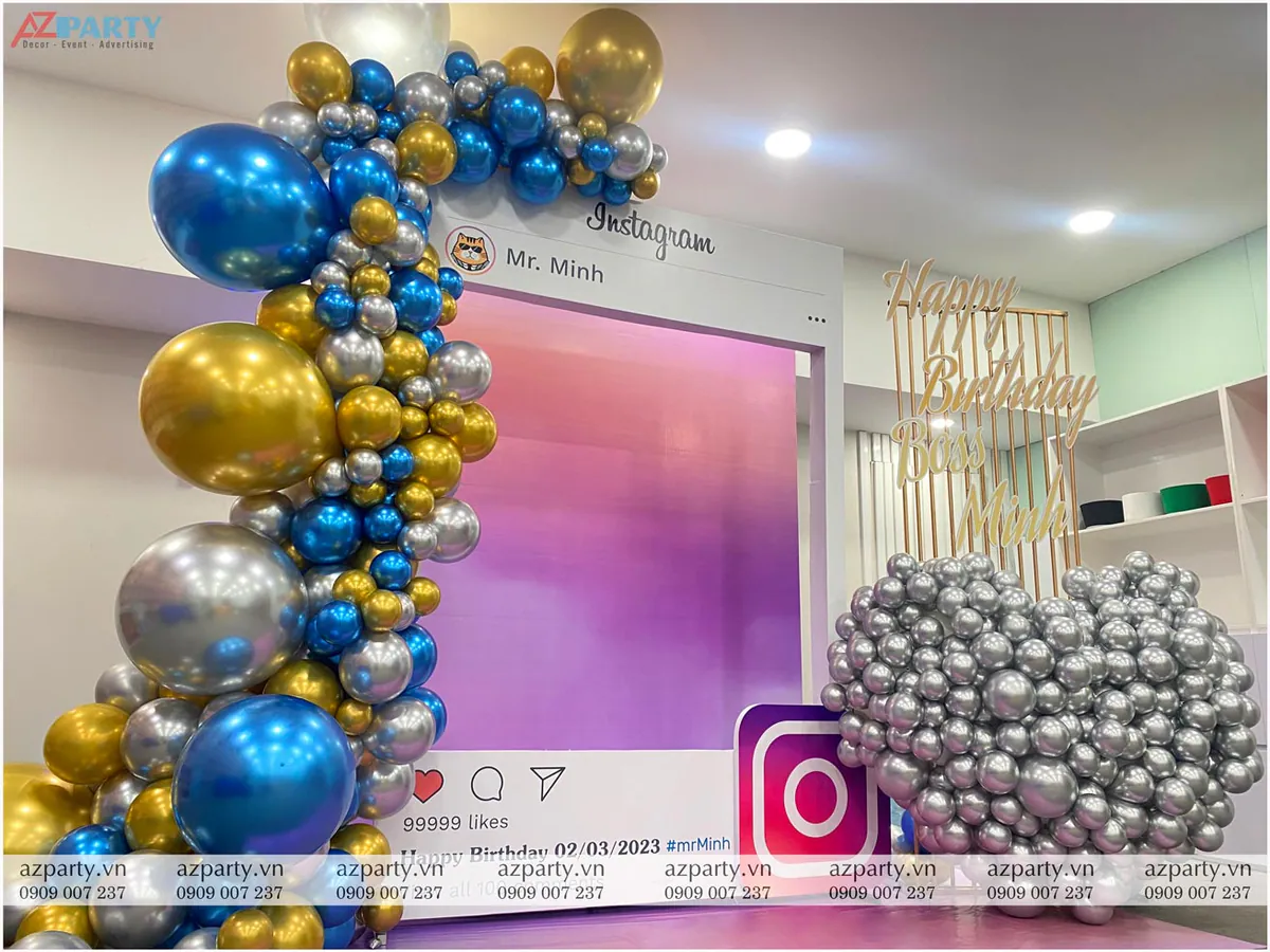 Góc chụp nghiêng cận cảnh cổng bóng bay chrome màu xanh dương, vàng gold và bạc đan xen trang trí cho backdrop Instagram sinh nhật sếp Minh.