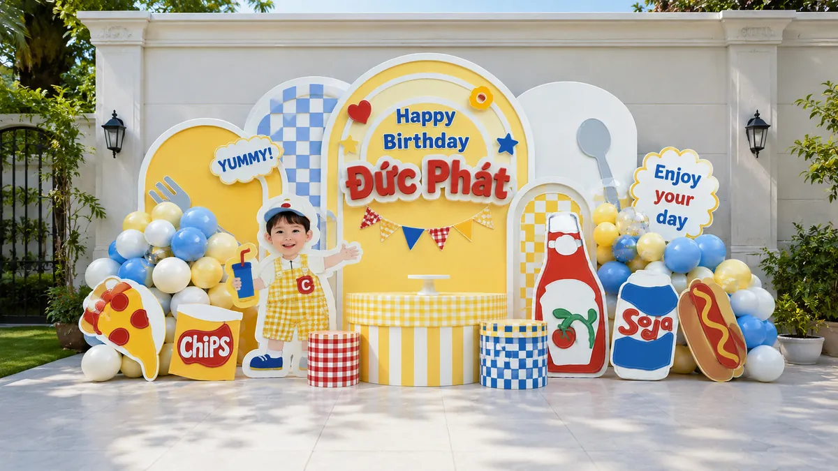 Set picnic ngoài sân màu vàng xanh với hộp chips, hotdog và cụm bóng