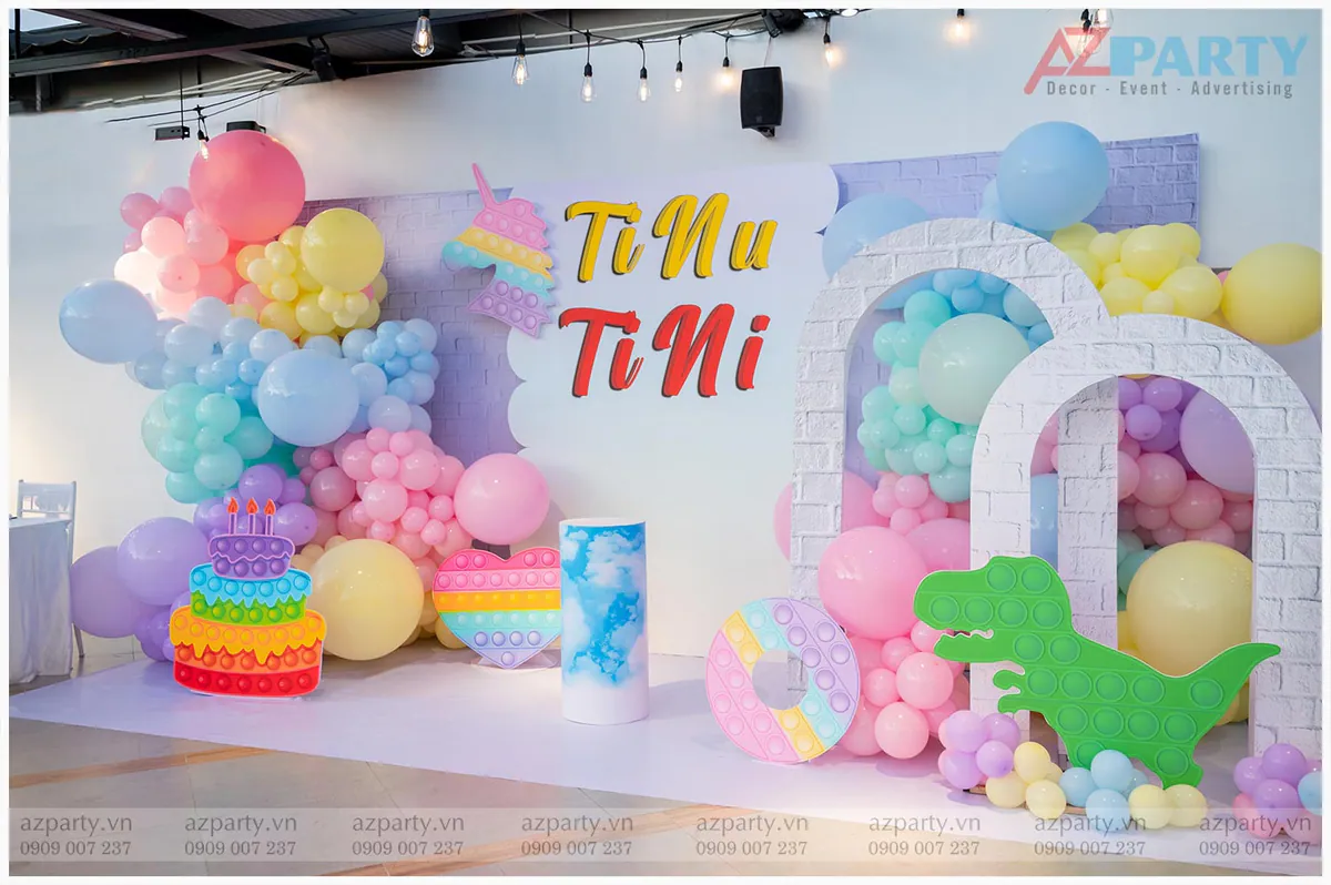 Trang trí tiệc sinh nhật bé TiNu và TiNi chủ đề Unicorn & Dino Pop It Candy màu pastel ngọt ngào với backdrop chữ nổi, các mô hình Pop It hình bánh sinh nhật, trái tim, khủng long, bánh donut cùng cổng bong bóng nghệ thuật vô cùng sống động.