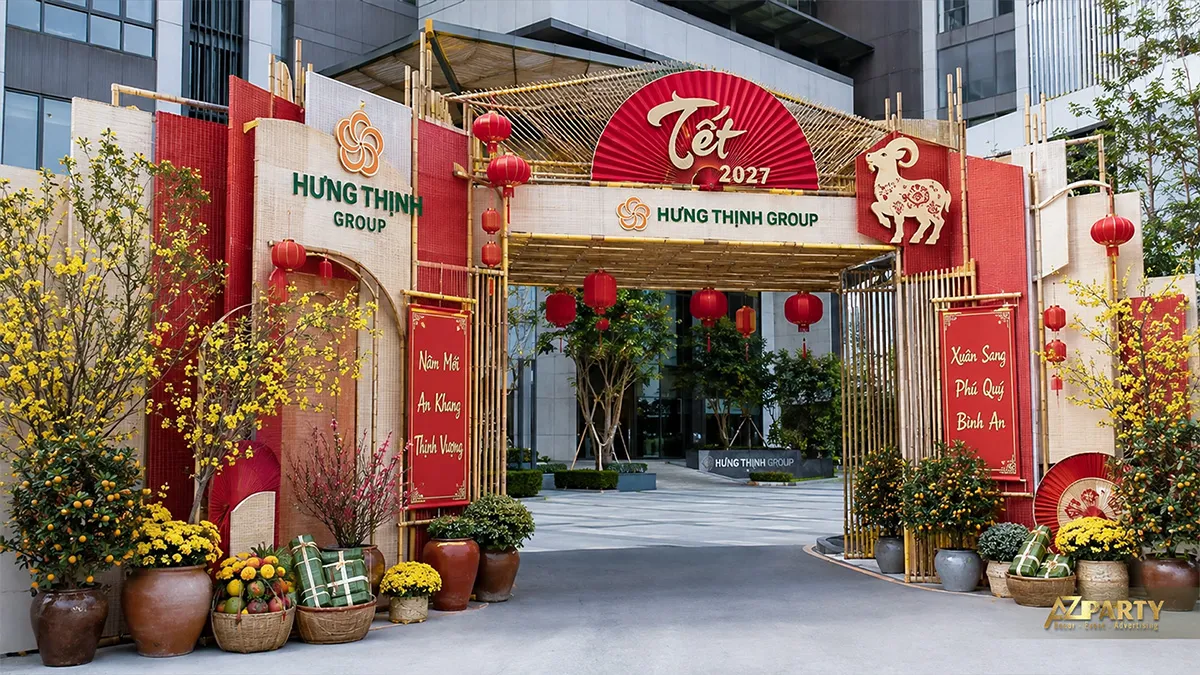 Cổng Tết Hưng Thịnh Group với khung tre đỏ kem, linh vật dê, mai vàng, cây quất và câu đối
