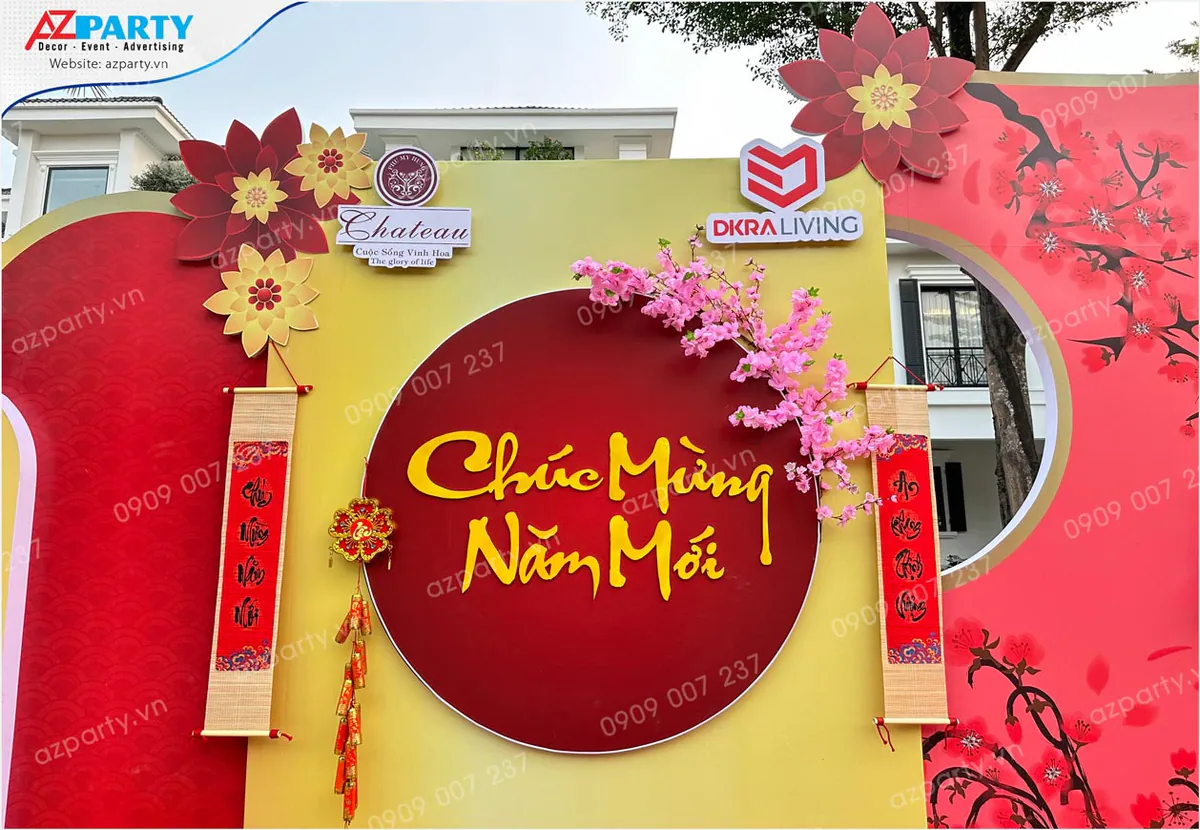 Chi tiết thiết kế trung tâm backdrop Tết với chữ 'Chúc Mừng Năm Mới' cách điệu, cành đào đào thắm, câu đối đỏ và pháo dây trang trí truyền thống