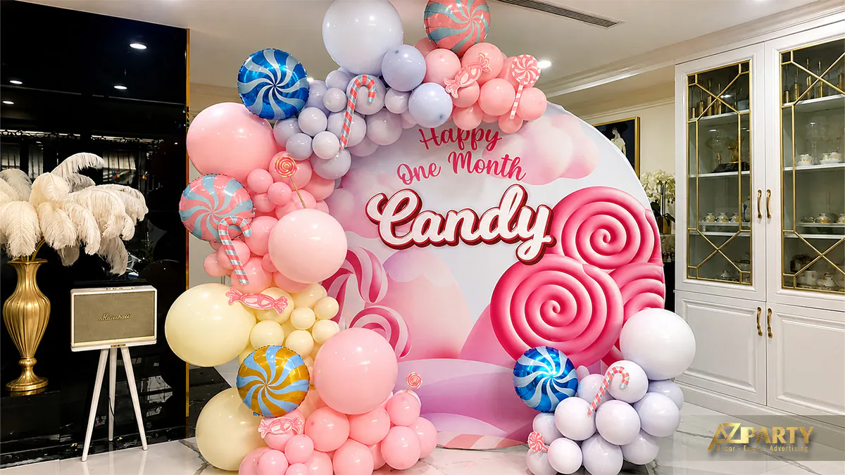 Góc chụp nghiêng giới thiệu photobooth đầy tháng bé Candy với trang trí bóng bay đủ sắc màu và các cây kẹo mút khổng lồ