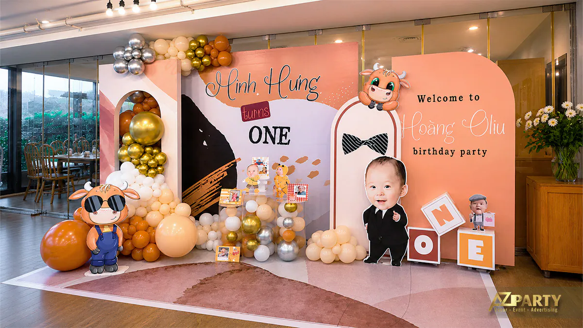Toàn cảnh sân khấu photobooth trang trí thôi nôi bé Minh Hưng (Hoàng Oliu) màu cam sữa và hình ảnh chú trâu vàng tinh nghịch