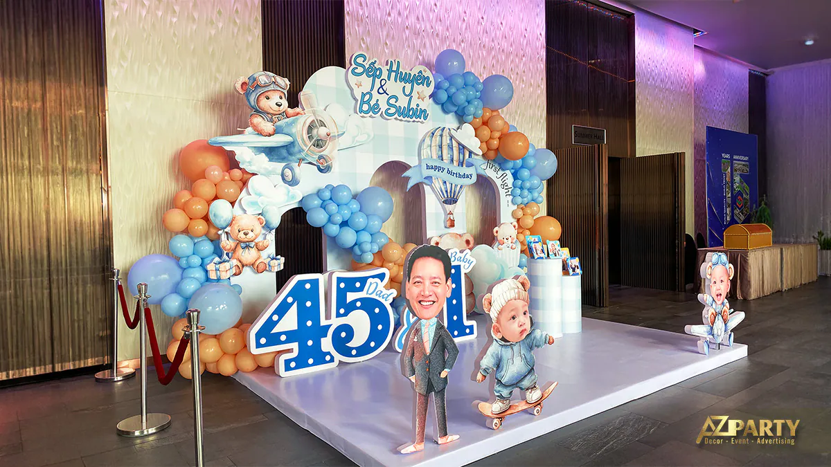 Góc nghiêng phông nền trang trí thôi nôi bé Subin và sinh nhật bố Huyên với mô hình chibi hài hước và bong bóng rực rỡ