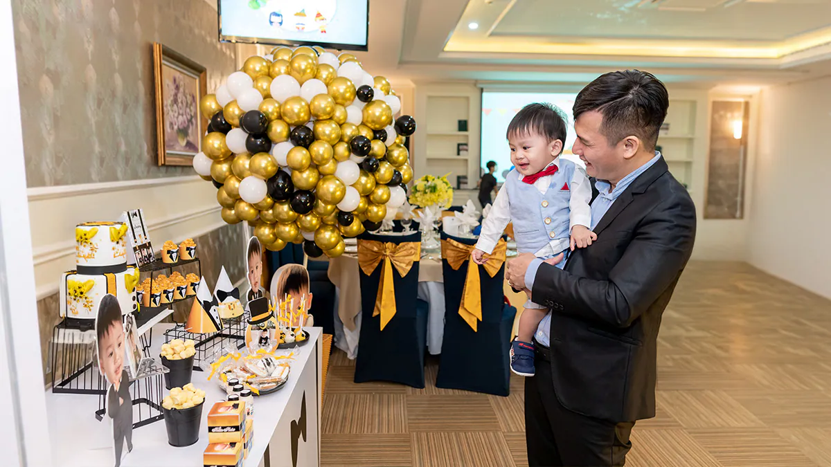 Góc nghiêng bàn bánh ngọt thôi nôi trưng bày nhiều loại bánh kem, cupcake và ảnh của bé