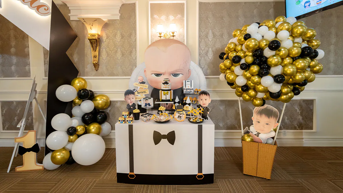 Bàn tiệc thôi nôi được trang trí sáng tạo theo phong cách áo sơ mi thắt nơ và dây đai