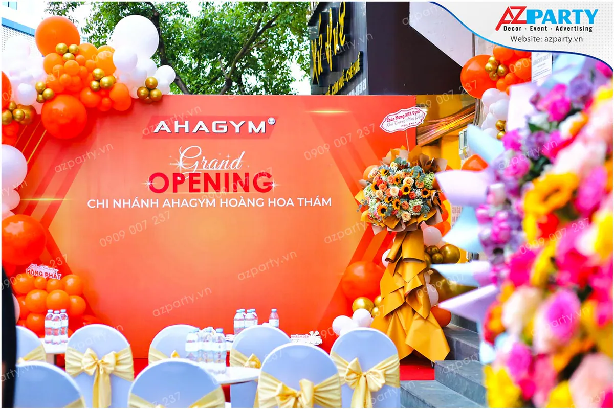 Sân khấu lễ khai trương phòng tập AHAGYM Hoàng Hoa Thám trang trí bóng bay cam trắng nổi bật.