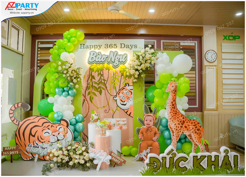Sân khấu trang trí tiệc thôi nôi chủ đề muông thú rừng xanh Safari cho bé Bảo Ngư (Đức Khải) có mô hình chú hổ con và chú hươu cao cổ đáng yêu.