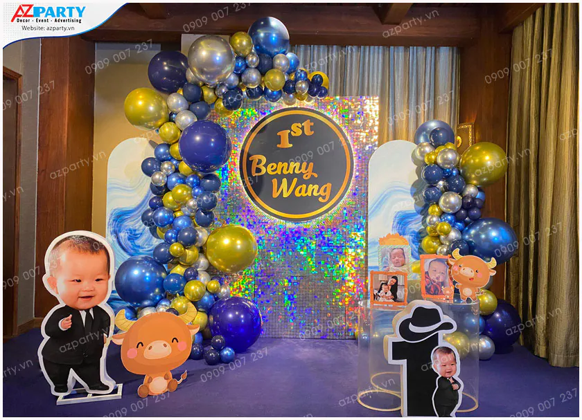 Khu vực check-in tiệc thôi nôi bé Benny Wang nổi bật với backdrop sequin ngũ sắc lấp lánh và cổng bong bóng màu xanh dương, vàng gold sang trọng.