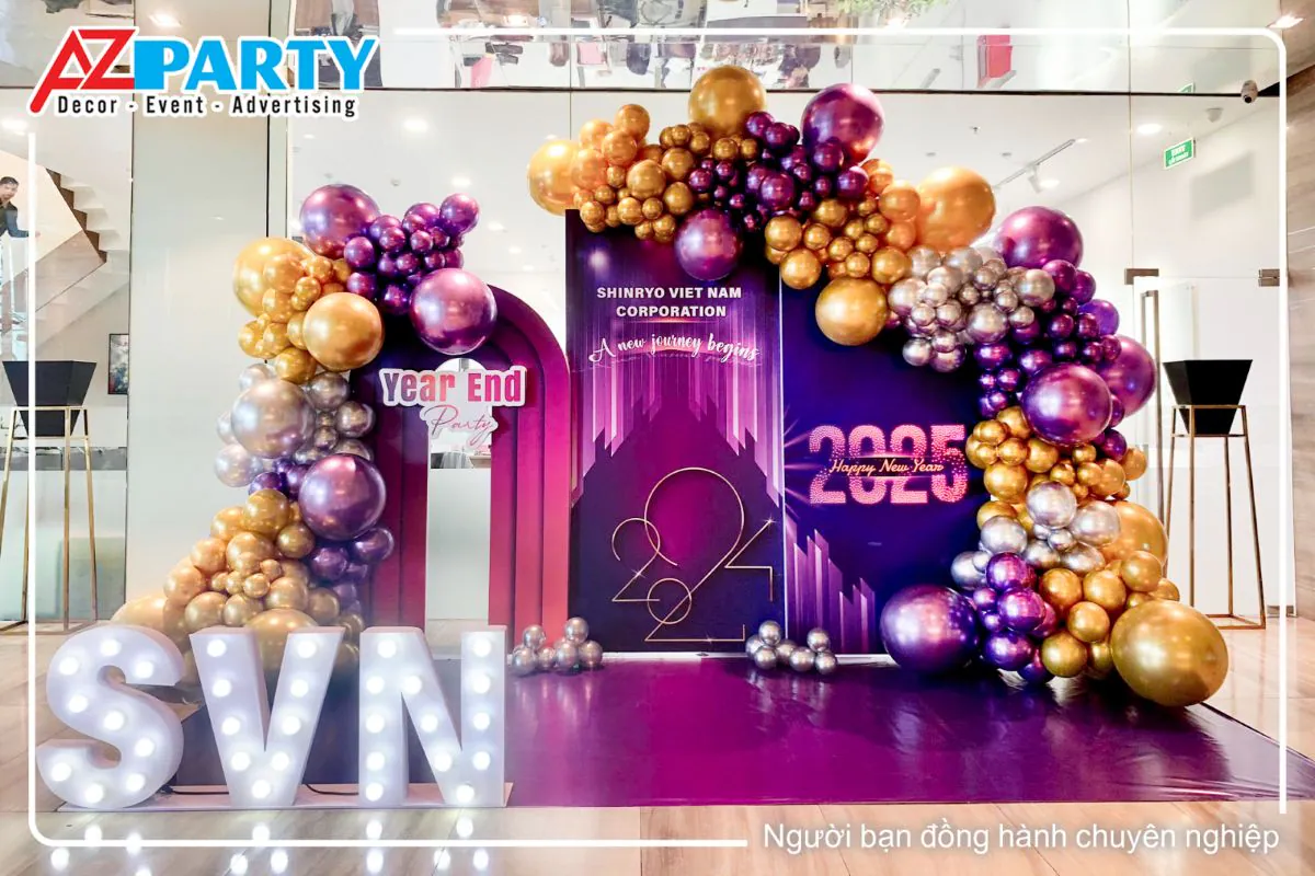 Backdrop Year End Party 2025 của Shinryo Vietnam Corporation được thiết kế hiện đại với tông màu tím chủ đạo, trang trí bóng bay nghệ thuật và chữ đèn LED SVN.