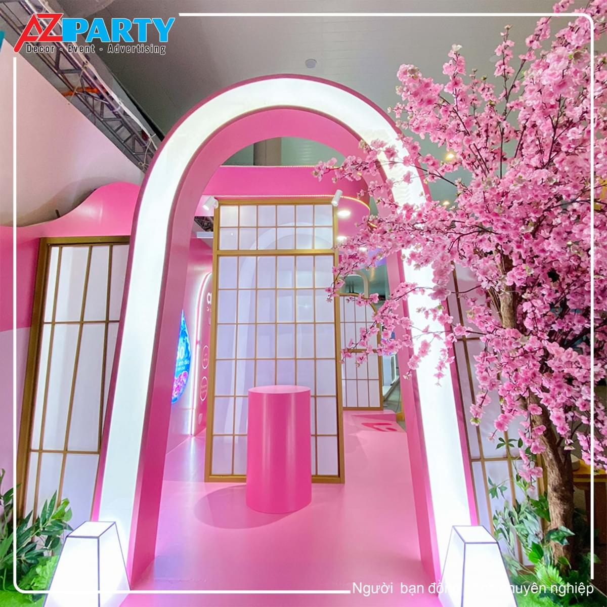cổng bên hông booth, được trang trí đèn và có cây đào ở bên phải