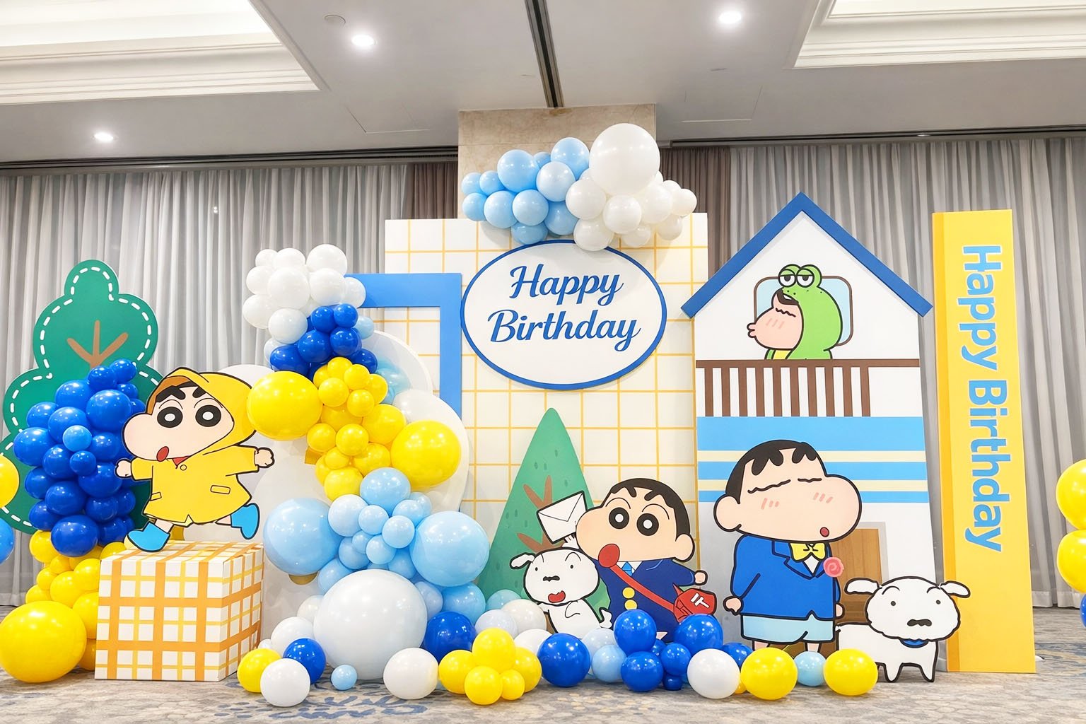 Backdrop sinh nhật chủ đề Shin cho bé trai với nhân vật Shin cậu bé bút chì, bóng bay xanh vàng và bảng Happy Birthday