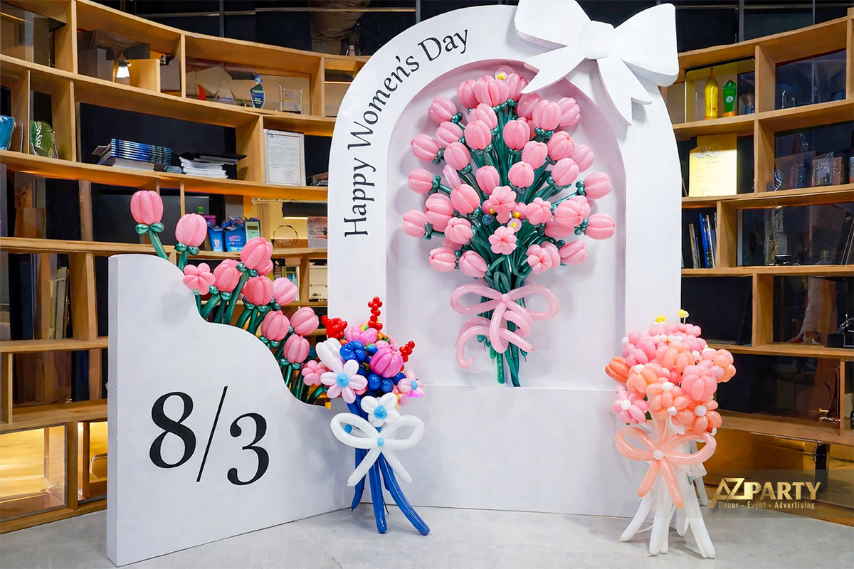 Backdrop trang trí 8/3 với khung vòm trắng, chữ “Happy Women’s Day”, số 8/3 nổi bật và các bó hoa bong bóng