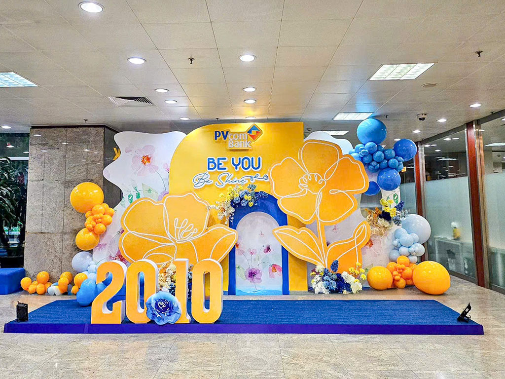 Backdrop 20/10 tone vàng xanh nổi bật với hoa cách điệu, bóng bay trang trí 