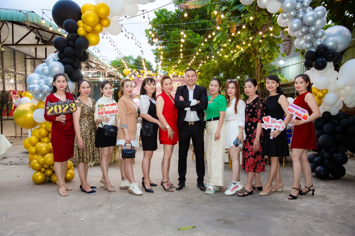 Giám đốc công ty Phi Lâm cùng nhóm nhân viên nữ chụp hình trong buổi tiệc tất niên tại cổng bóng