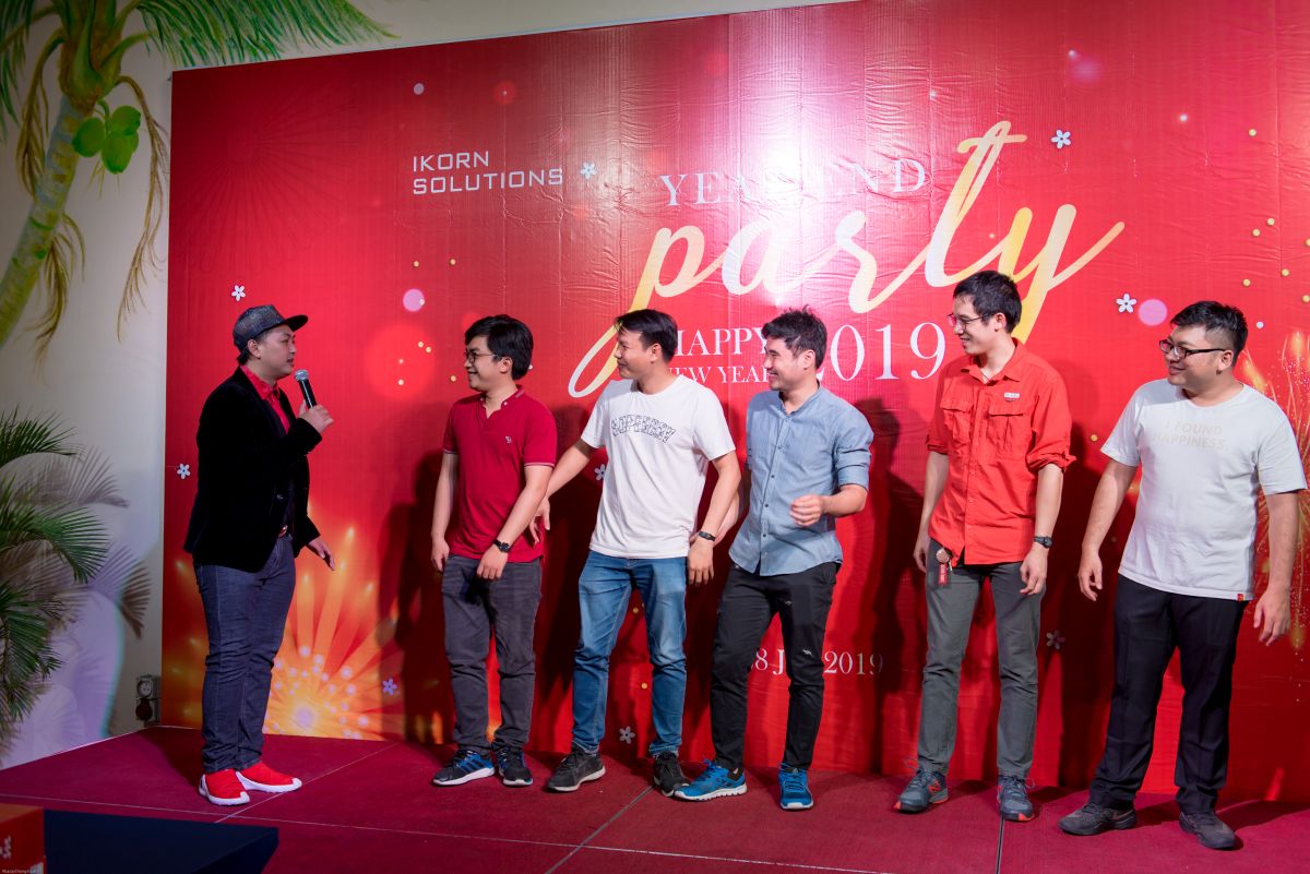 Nhóm nhân viên nam lên sân khấu tham gia vào trò chơi trong buổi tiệc tất niên dưới sự dẫn dắt của MC