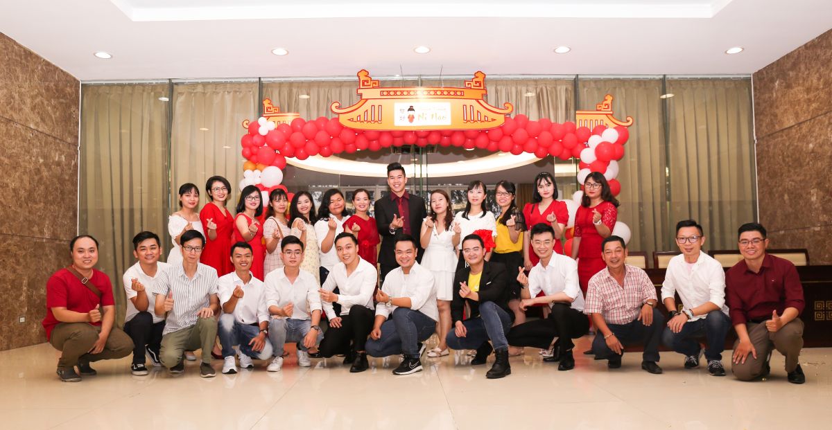 tập thể đội ngũ Ni Hao check in tại cổng chào với kiểu thả tim
