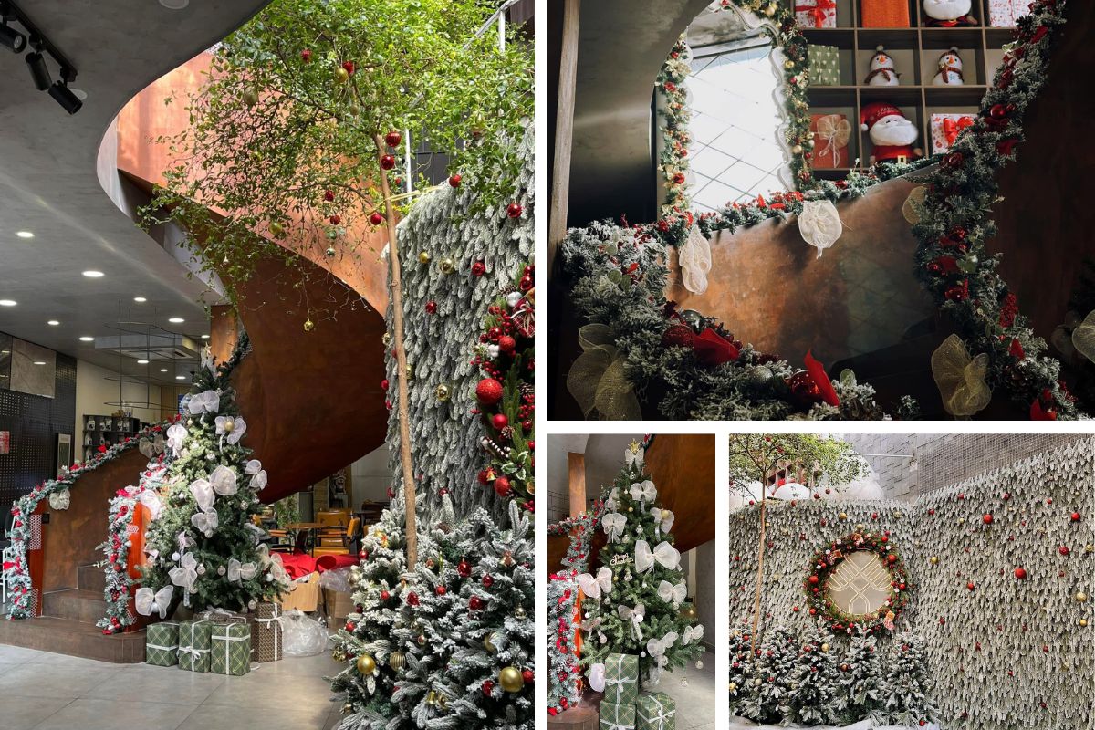 Không gian quán được trang trí Giáng sinh với cầu thang xoắn đồng màu ấm, cây thông phủ tuyết trắng và vòng hoa lớn gắn nơ đỏ nổi bật. Các chi tiết như hộp quà, dây kim tuyến và ánh đèn vàng mang lại cảm giác sang trọng và ấm áp giữa không gian hiện đại.