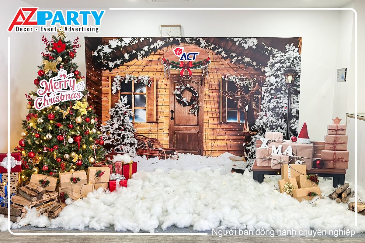 Tiểu cảnh noel công ty ACT theo phong cách Rustic, ở giữa là ngôi nhà gỗ giữa rừng thông, bên cạnh là cây thông noel được decor rực rõ với quả châu đỏ và vàng, dưới gốc cây thông là những hộp quà noel 