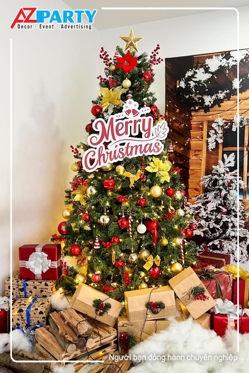 cây thông noel màu xanh với những quả châu đỏ vàng, xung quanh là dây đèn vàng lấp lánh, trên thân cây được để dòng chữ "Merry Chrismas"