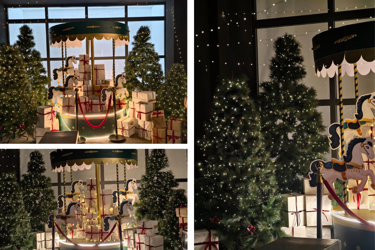 Góc trang trí Giáng sinh với vòng xoay ngựa gỗ, cây thông phủ đèn và những hộp quà lớn được gói nơ đỏ. Ánh đèn vàng tạo nên khung cảnh ấm áp, mang cảm giác hoài niệm và cổ tích giữa không gian quán.