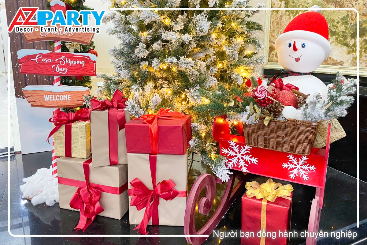 chú người tuyết ngồi trên xe trượt, bên cạnh là những hộp quà