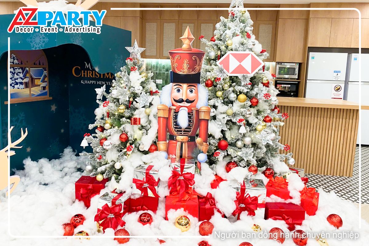 Chú lính chì mặc bộ quân phục màu đó, đứng giữa hai cây thông, dưới chân là những hộp quà màu đỏ phủ tuyết trắng