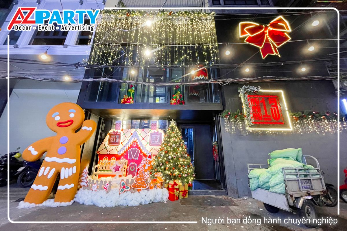 Tiểu cảnh noel tại khu 13 Club. Được trang trí theo concept ngôi nhà bánh gừng, nổi bật là hình ảnh cậu bé bánh gừng khổng lồ đứng vẫy tay chào, bên cạnh là ngôi nhà bánh gừng cùng cây thông noel. Cửa kính được treo những dây đèn led vàng lấp lánh, phần tưởng còn lại được treo 1 chiếc nơ đỏ có đèn neon bao quanh, bên dưới là logo của khu 13 club 