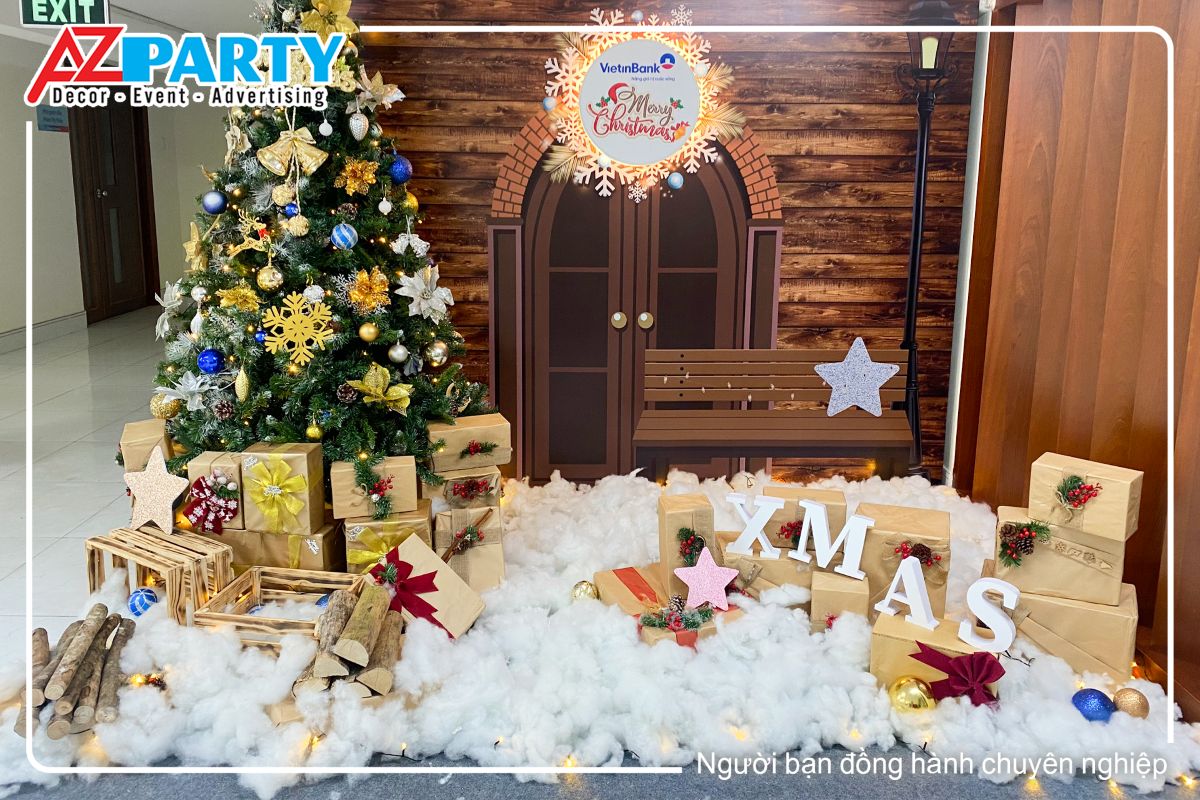 cận cảnh tiểu cảnh tại khu vực làm việc của nhân viên với backdrop là hình ảnh ngôi nhà gỗ nâu, phía trước là cây thoongn noel rực rỡ cùng những hộp quà