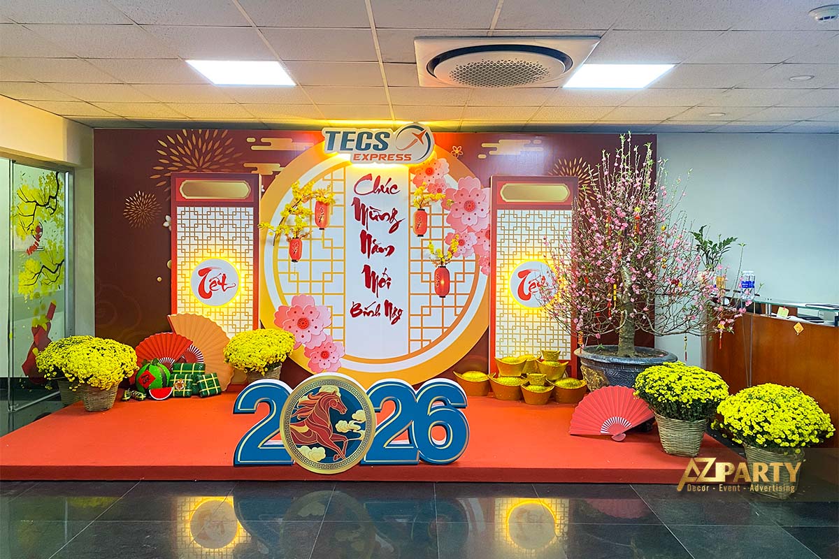 Tiểu cảnh trang trí Tết 2026 tại văn phòng TECS Express với hoa mai, hoa đào, đồng tiền vàng và backdrop Tết truyền thống