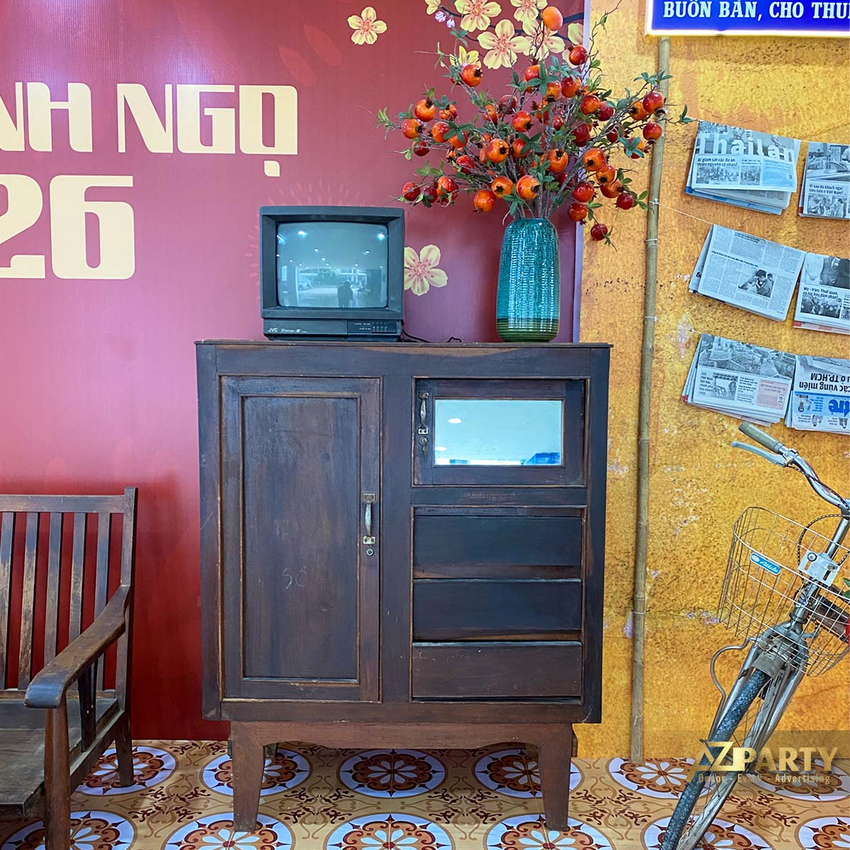 Tủ gỗ cổ đặt tivi đen trắng và bình hoa trang trí trong tiểu cảnh Tết xưa