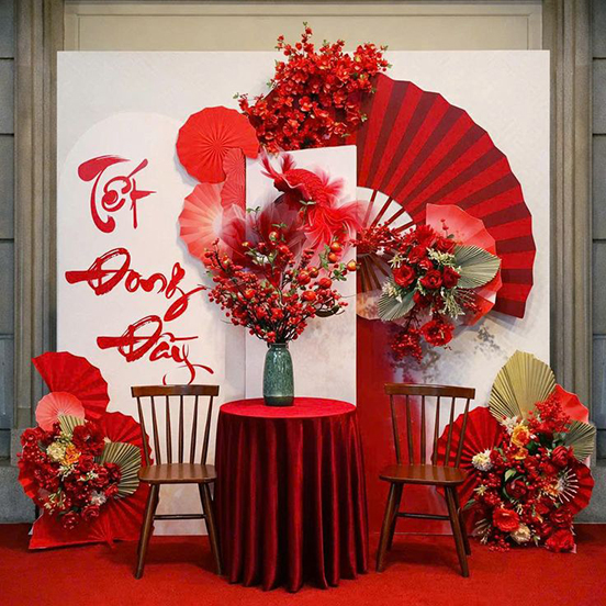 Tiểu cảnh decor Tết tông đỏ nghệ thuật với quạt giấy, hoa đỏ và bàn ghế ngồi
