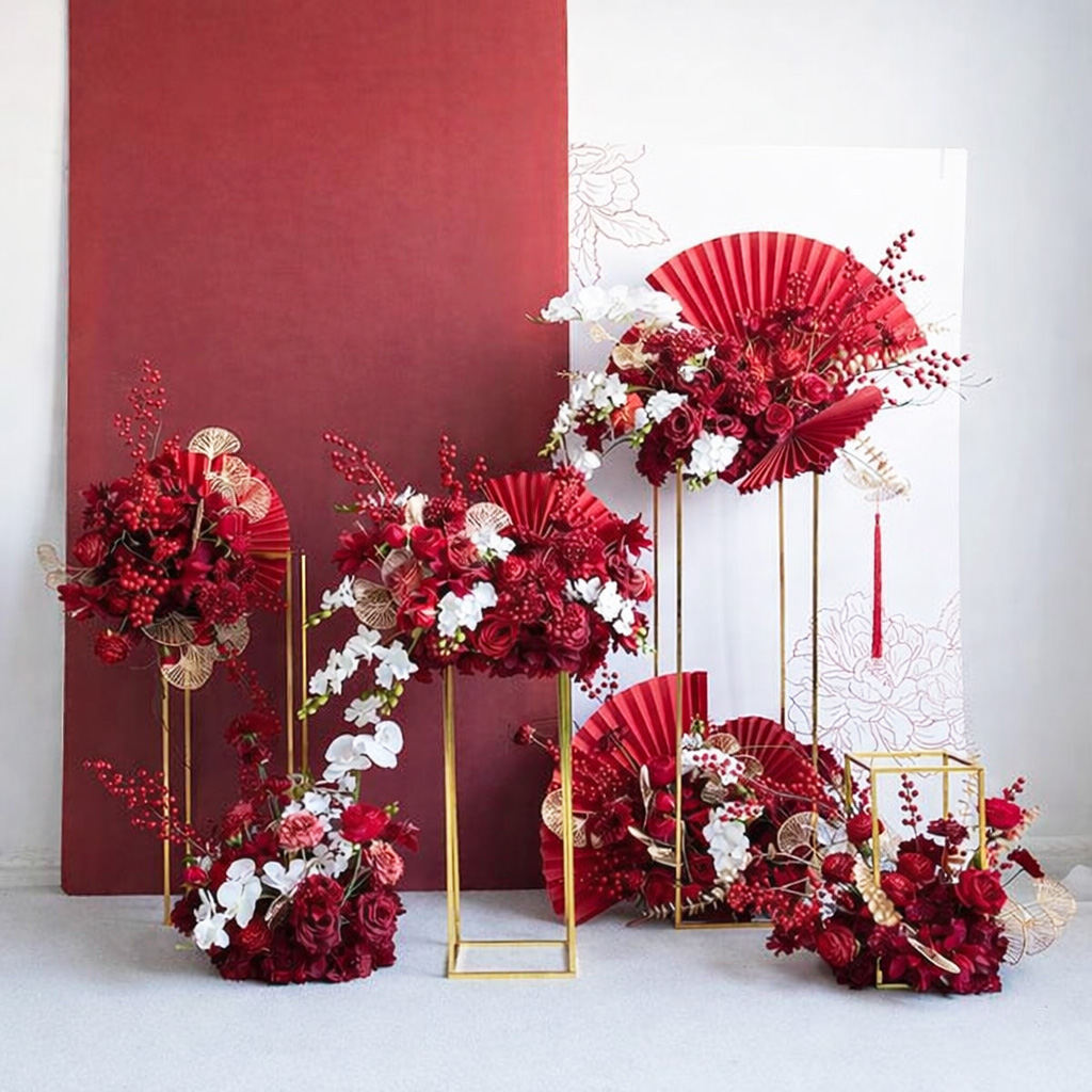 Tiểu cảnh decor Tết tone đỏ trắng với quạt giấy, hoa đỏ – trắng và khung kim loại vàng, phong cách sang trọng hiện đại.