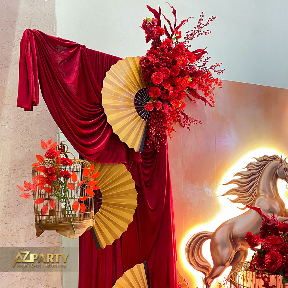 Chi tiết trang trí Tết 2026 với hoa đỏ, quạt giấy vàng, lồng chim treo và rèm vải đỏ sang trọng