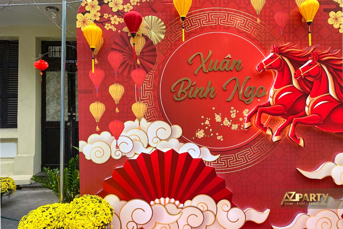 Cận cảnh backdrop trang trí Tết Xuân Bính Ngọ với nền đỏ, chữ Xuân Bính Ngọ nổi bật, đèn lồng treo, họa tiết mây, quạt cổ truyền 