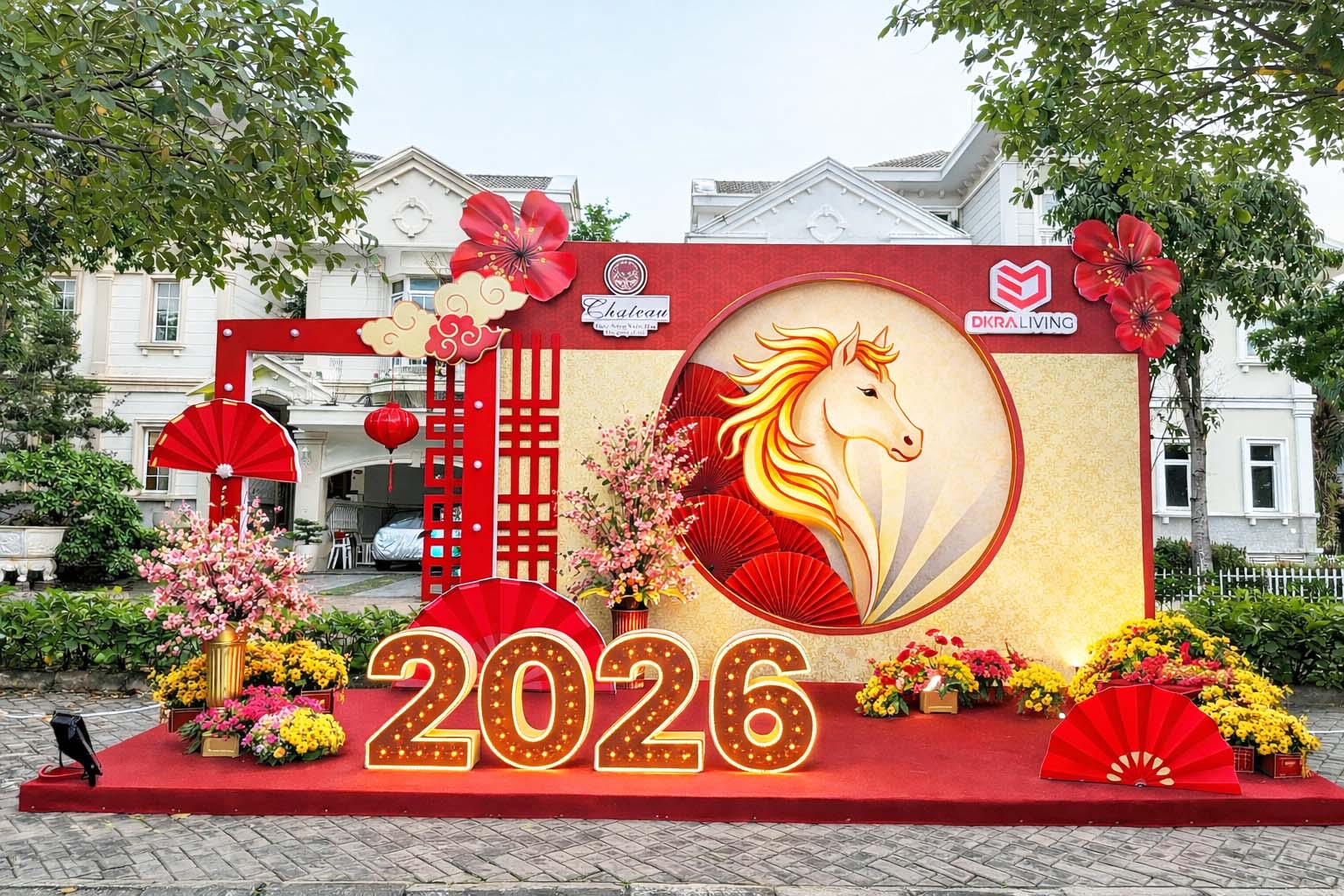 Tiểu cảnh trang trí Tết Xuân Bính Ngọ 2026 ngoài trời với phông đỏ vàng sang trọng, hình ngựa cách điệu phát sáng, quạt trang trí, hoa xuân rực rỡ