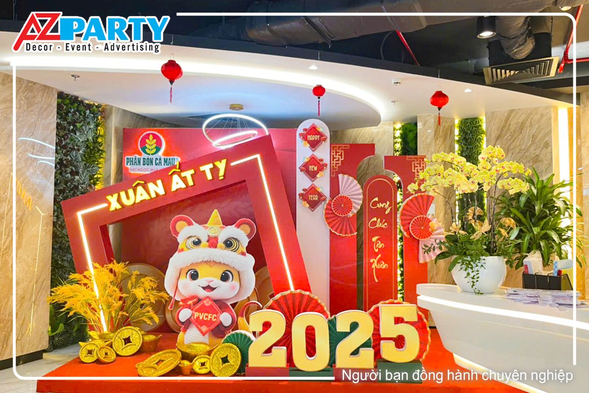 toàn cảnh tiểu cảnh tết Ất Tỵ tại công ty phân bón Cà Mau. Chính giữa tiểu cảnh là linh vật chú rắn đội mũ lân, bên cạnh là dòng chữ 2025 nổi bật, phía sau là cụm lúa và logo thương hiệu của công ty