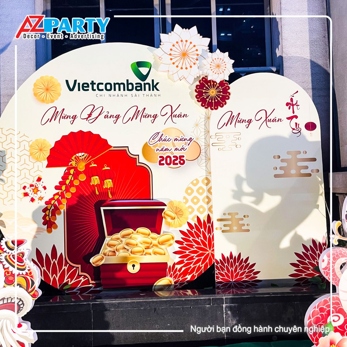 cận cảnh backdrop phía sau được trang trí bằng họa tiết hòm tiền vàng, dòng chữ Mừng Đảng Mừng xuân nổi bật và logo thương hiệu của Vietcombank