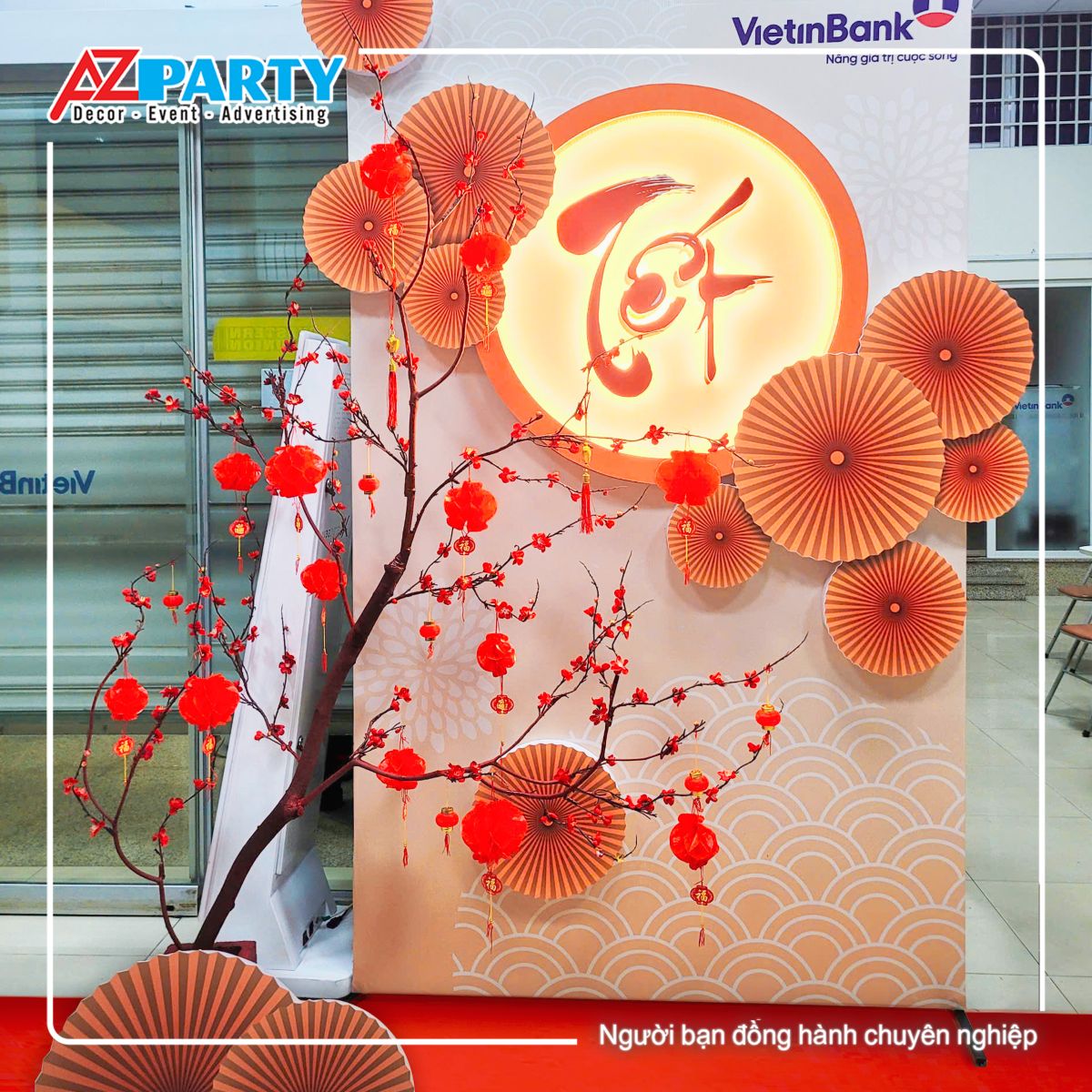 tiểu cảnh tết với hoa đào, quạt giầy, và dòng chữ Tết thư pháp nổi bật 