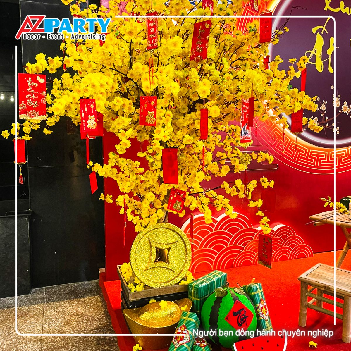 cây mai vàng, trên cây có treo các túi lì xì đỏ, dưới gốc cây có đồng tiền vàng, bánh trưng và bánh tét